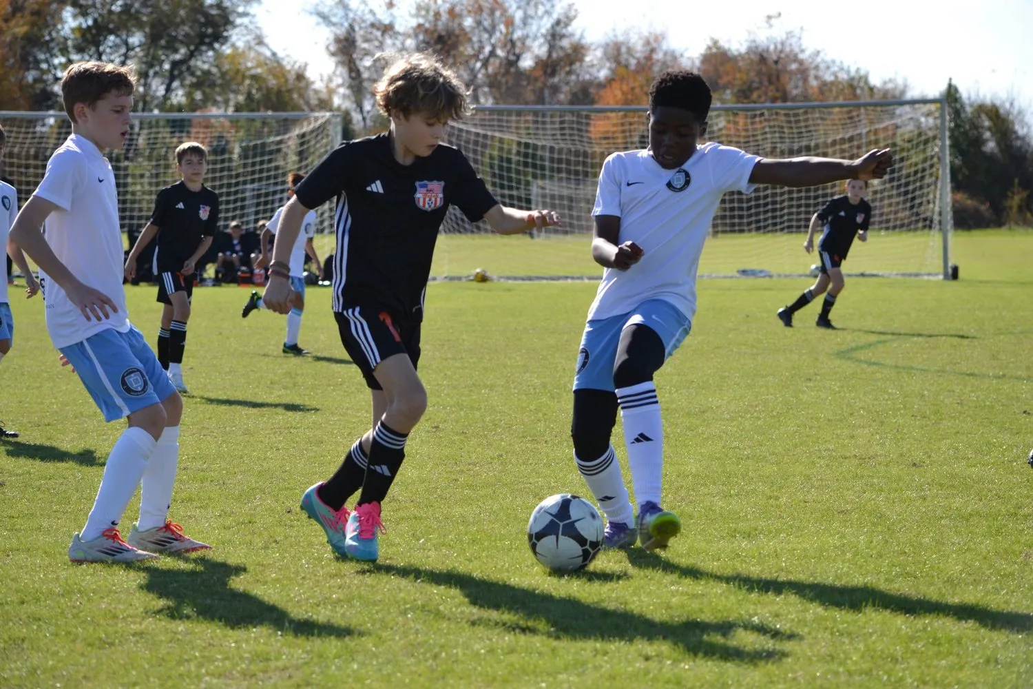 A Rebels player in black dribbling between two opponents in white